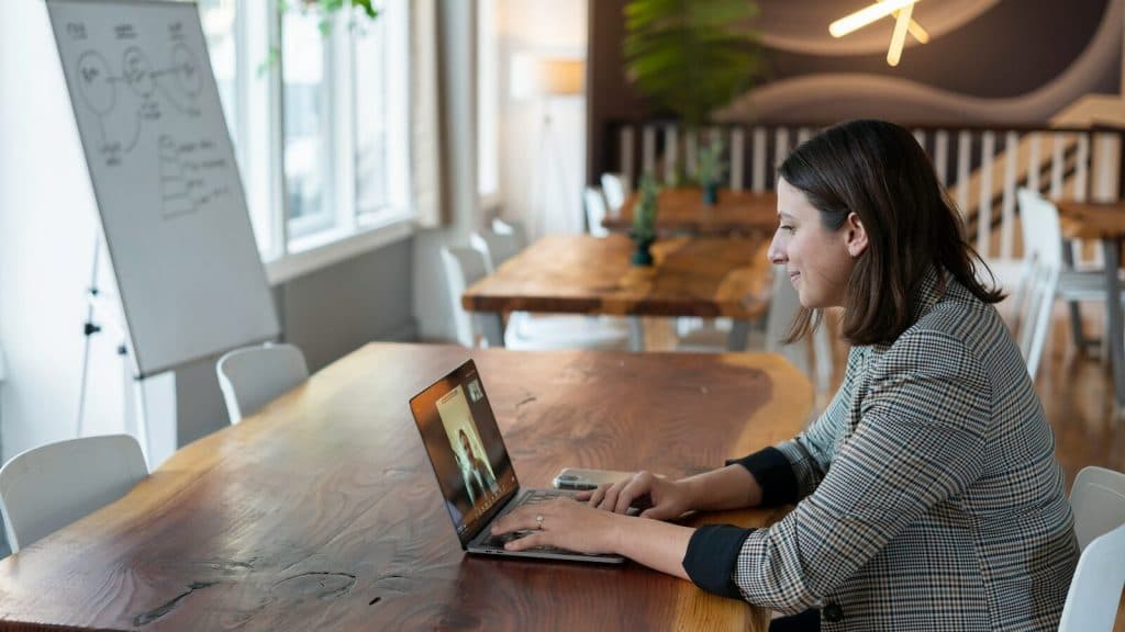 woman in gray and white striped long sleeve shirt using silver macbook